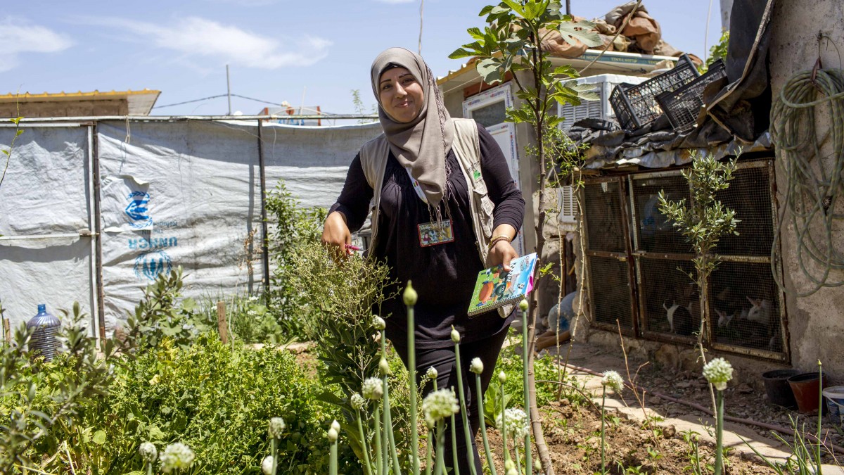 Syrian refugee and local community outreach officer from the NGO Lemon Tree Trust visiting a home garden in Domiz Refugee Camp, Iraq.