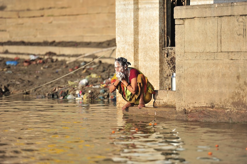 Woman washes her face in the river Ganga