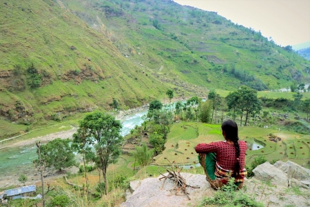 Woman looking over river valley, in Nepal