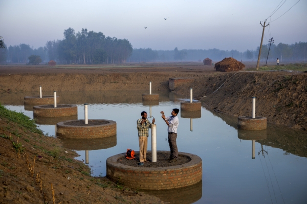 A scientist measures the water collected in the pond created under the UTFI initiative developed by IWMI scientists in the Jiwai Jadid village.