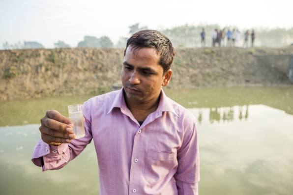 A scientist holding a sample of water taken from water collected pond