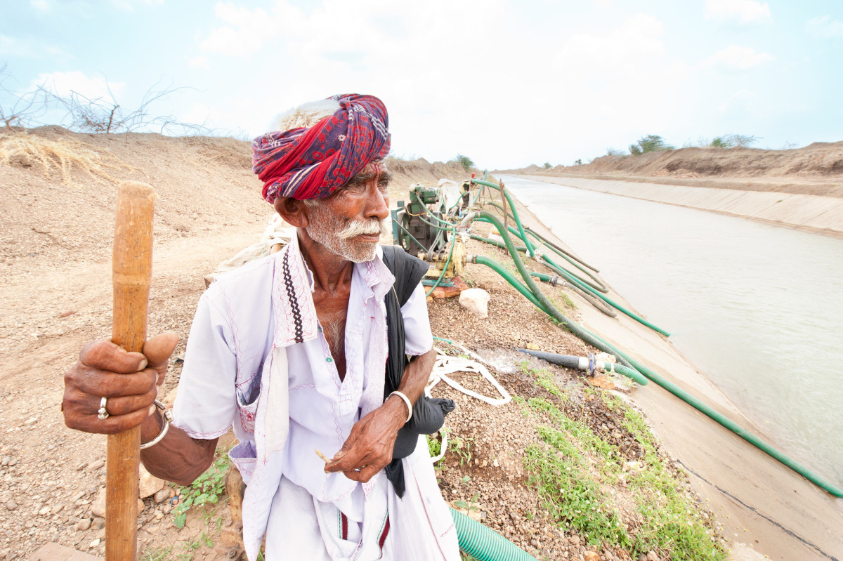 Farmer in Gujarat looks on as irrigation pumps and pipes pull water from the canal for farms. (Photo: Hamish John Appleby / IWMI)