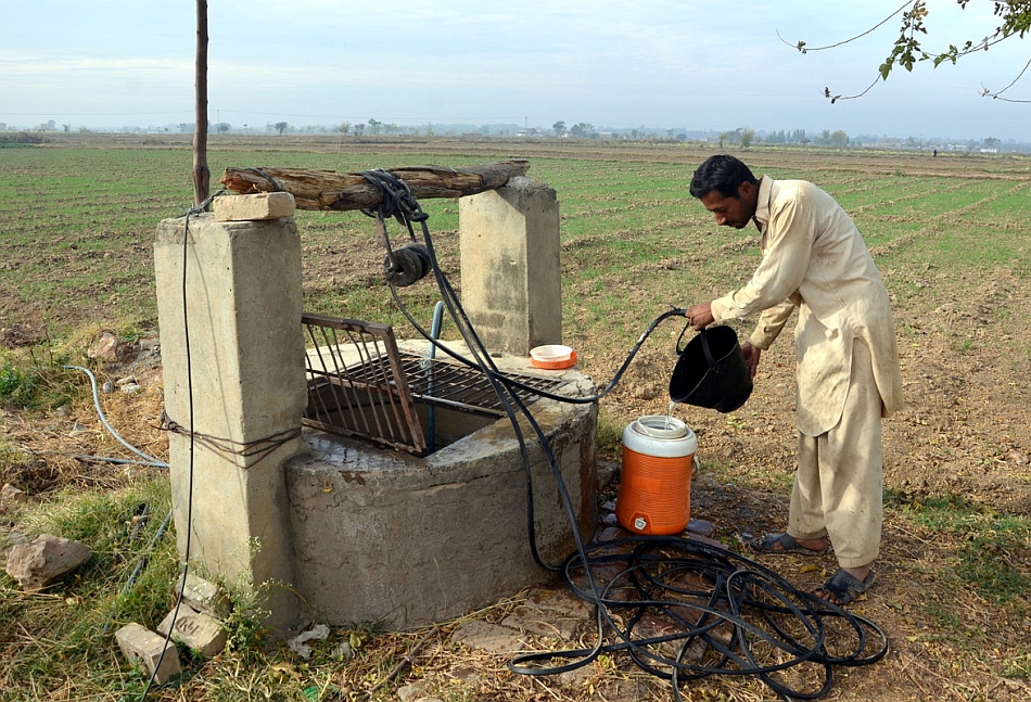 A farmer filling drinking water in cooler from a well. Photo: Picasa