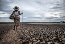 Women standing on dry soil and fishing gear, global warming and