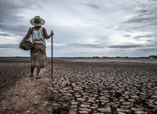 Women standing on dry soil and fishing gear, global warming and